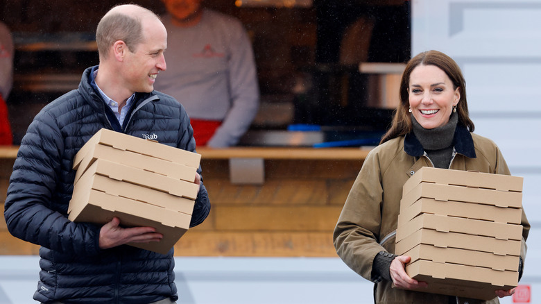 Prince William and Kate Middleston carry pizza boxes