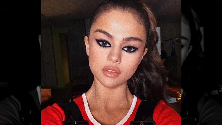 Selena Gomez taking a selfie with dramatic cat-eye makeup