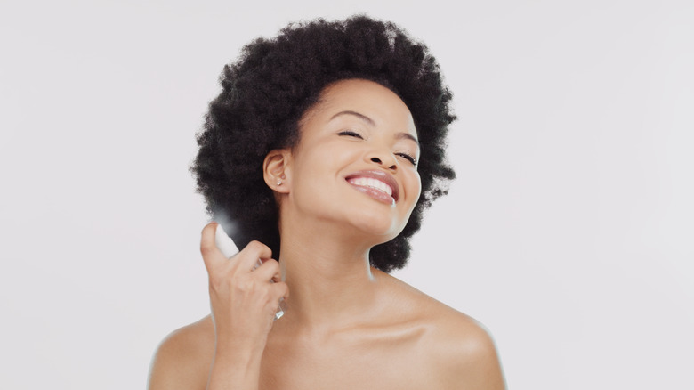 Woman spraying perfume in hair