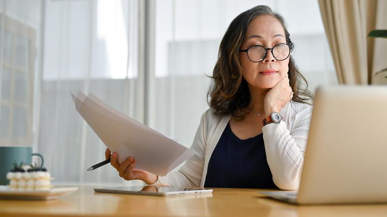 woman looking over documents and at computer