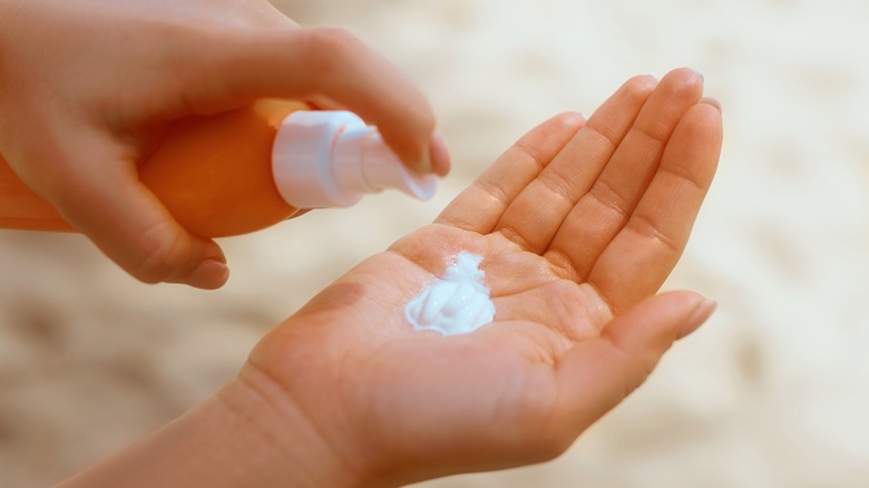 woman squeezing sunscreen on hands