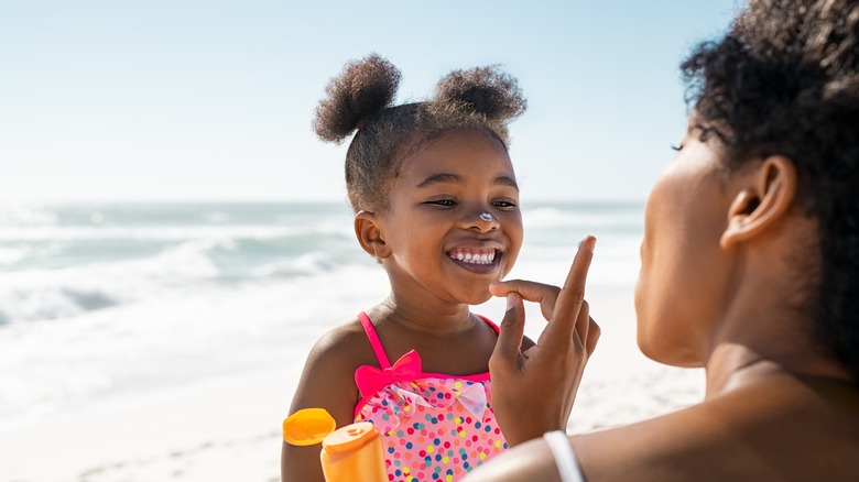 Woman applying sunscreen on girl