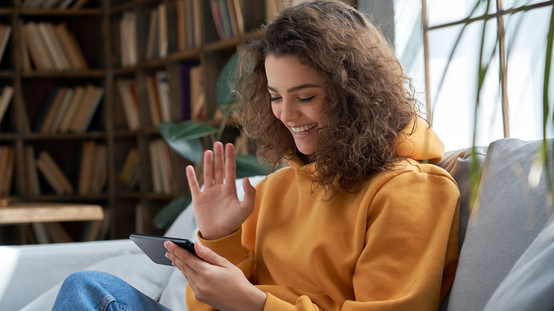 girl smiling and waving at phone