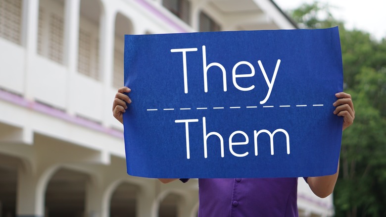 Man holding they/them sign