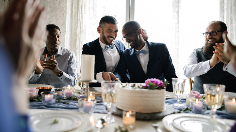 Men cutting wedding cake