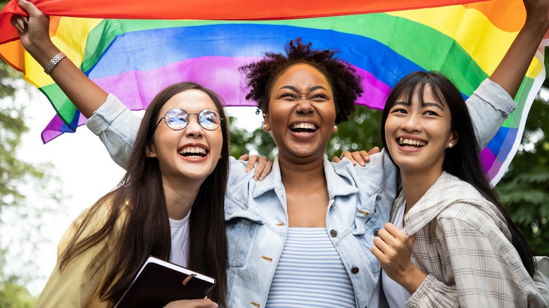 Women stand with rainbow flag