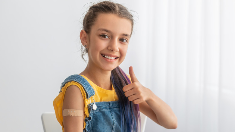 Child wearing bandage giving thumbs up