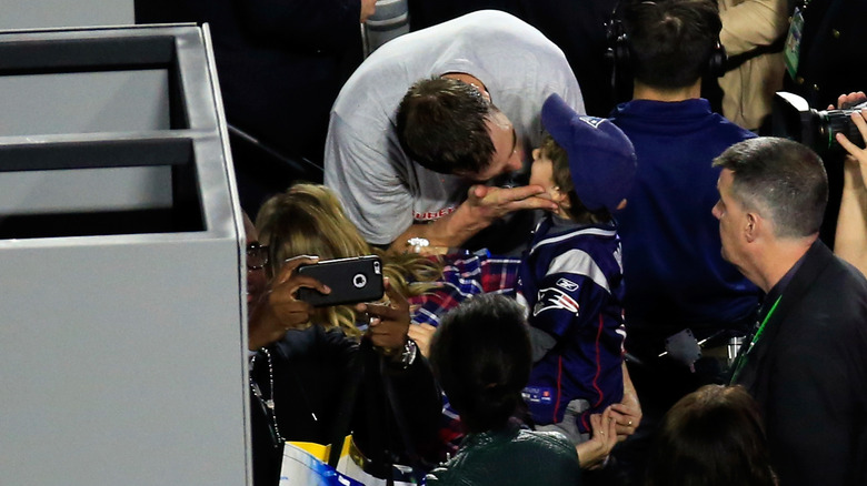 Former New England Patriot Tom Brady kisses son after defeating the Seattle Sea Hawks at Super Bowl XLIX