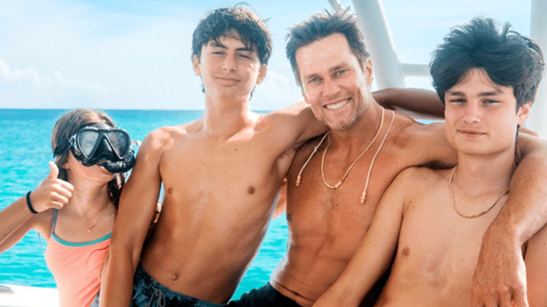 Tom Brady smiling with his three children on a boat