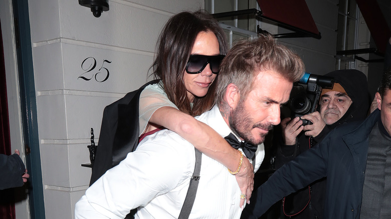 David Beckham giving Victoria Beckham a piggy back ride