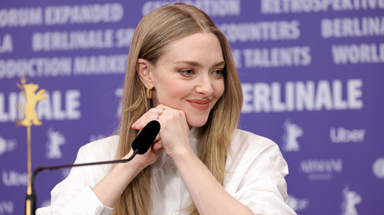 Amanda Seyfried sitting with hands clasped at the microphone