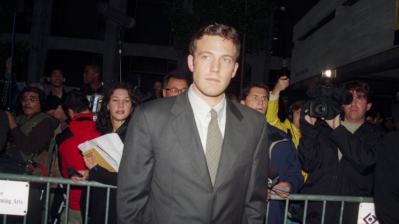 Ben Affleck in a gray suit surrounded by fans