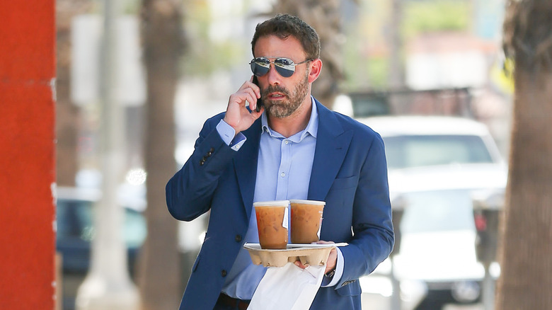 Ben Affleck talking on the phone with coffee tray in hand