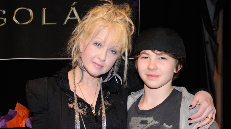 Cyndi Lauper in black with silver chains and Declyn Lauper in black tee shirt, jacket, and hat