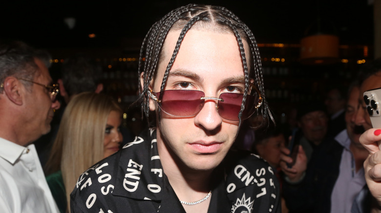 Declyn Lauper in black shirt with white letters, sunglasses, and braids