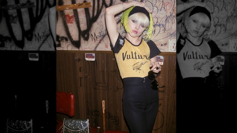 Debbie Harry wtih yellow wig wearing Vulture tee shirt and black pants