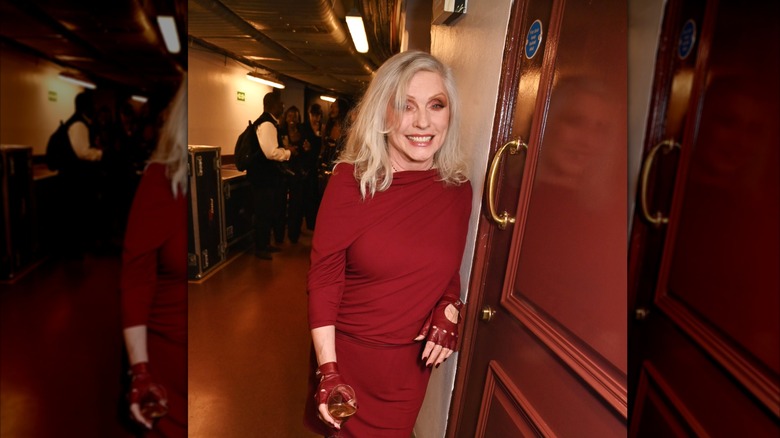 Debbie Harry in red dress and red gloves holding a drink