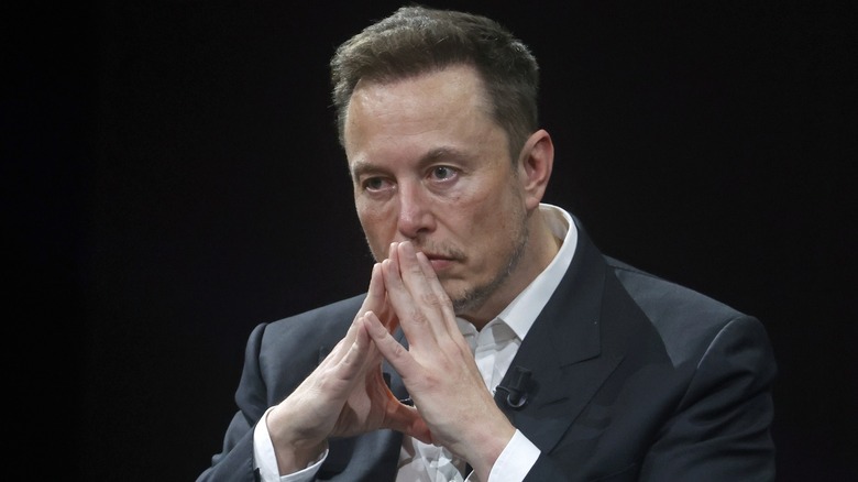 Elon Musk looking contemplative with his fingers steepled