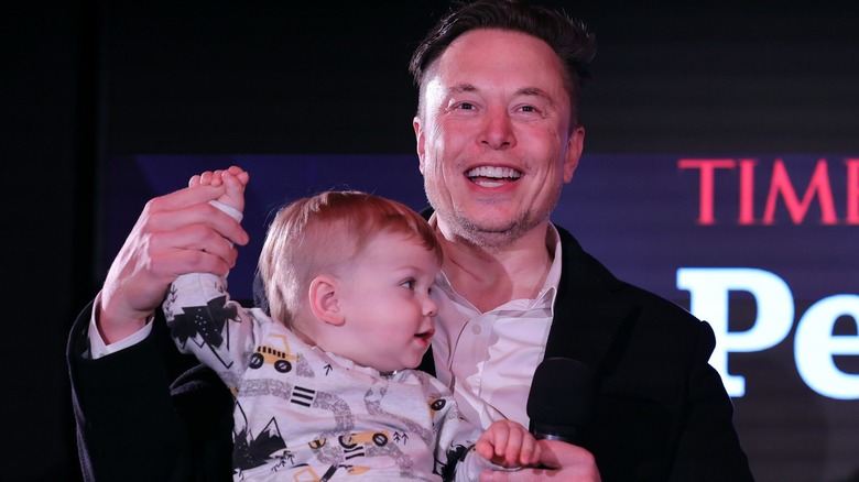 Elon Musk holding his son X's hand in the air