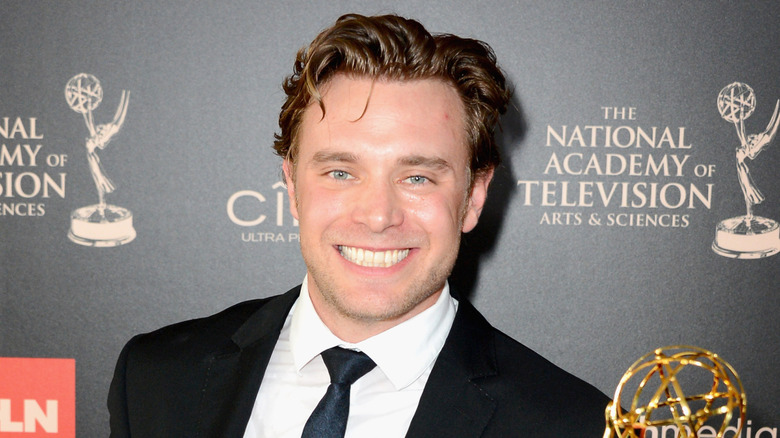 billy miller smiling while holding daytime emmy