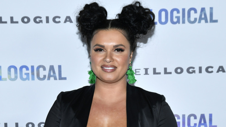 Joy Taylor smiles in green earrings at an event