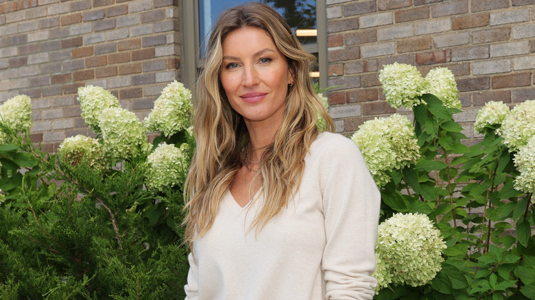 Gisele Bundchen posing in front of greenery