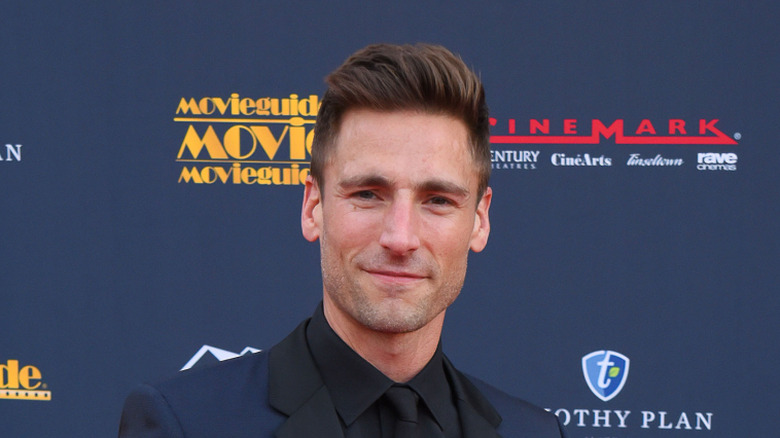 Andrew Walker smiling in a dark suit at an event