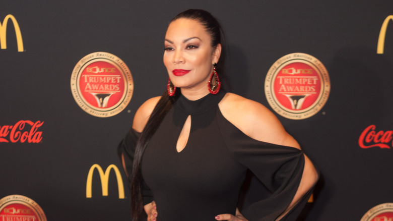 Egypt Sherrod poses in front of black banner with McDonald's and Coca-Cola logos