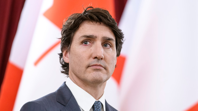 Justin Trudeau stands in front of the Canadian flag