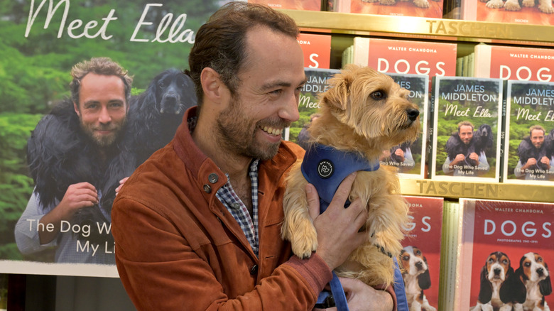 James Middleton poses with a fan's dog at a book signing in 2024