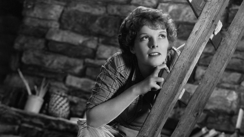 Katharine Hepburn poses while climbing up a ladder