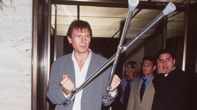 Liam Neeson shows off his walking crutches in 2000