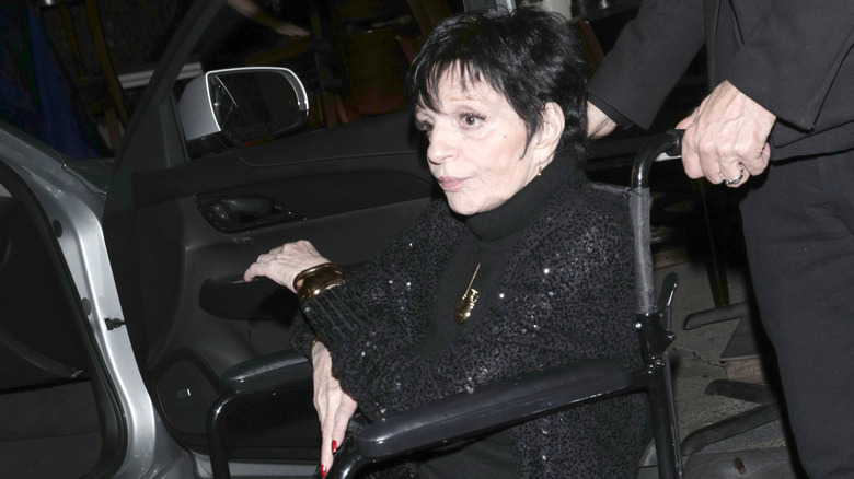 Liza Minnelli being wheeled in wheel chair to car