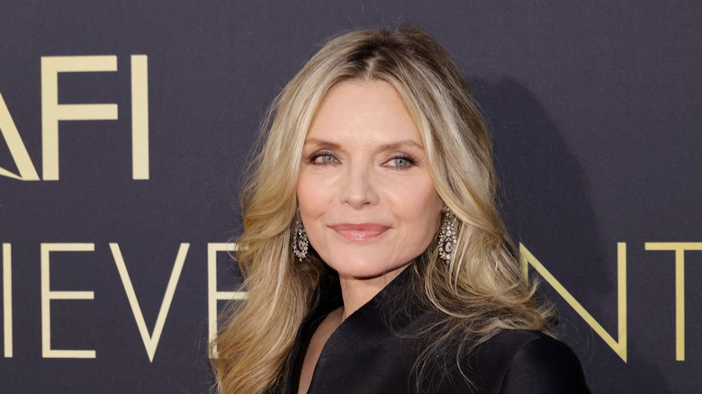 Michelle Pfeiffer in black coat and dangle earrings