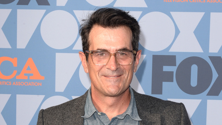 Ty Burrell smiling in front of blue backdrop