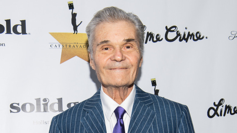 Fred Willard standing in front of white backdrop