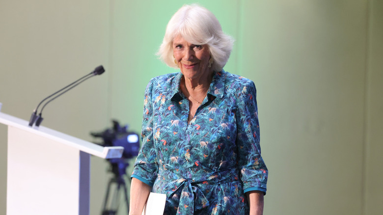 Queen Camilla smiling next to podium