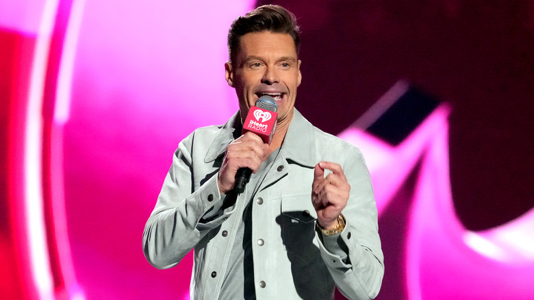 Ryan Seacrest with a microphone on stage