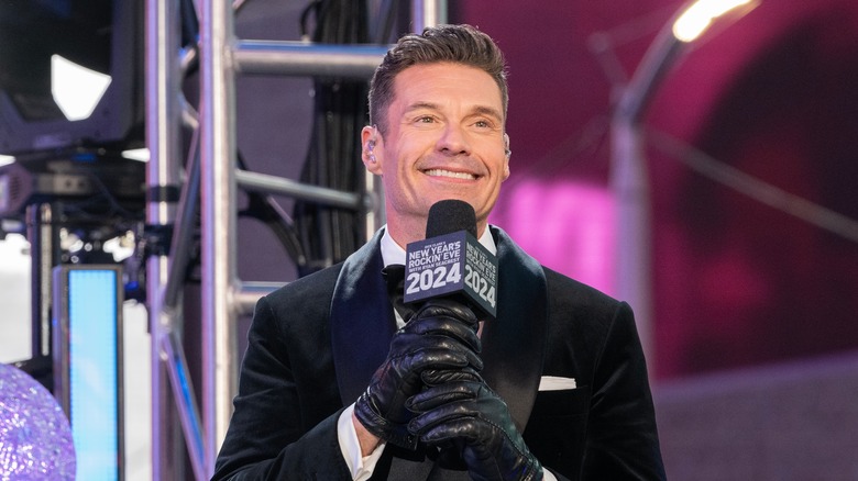 Ryan Seacrest smiling and holding a microphone