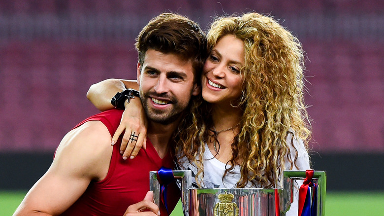 Shakira posing with Gerard Pique and his trophy 