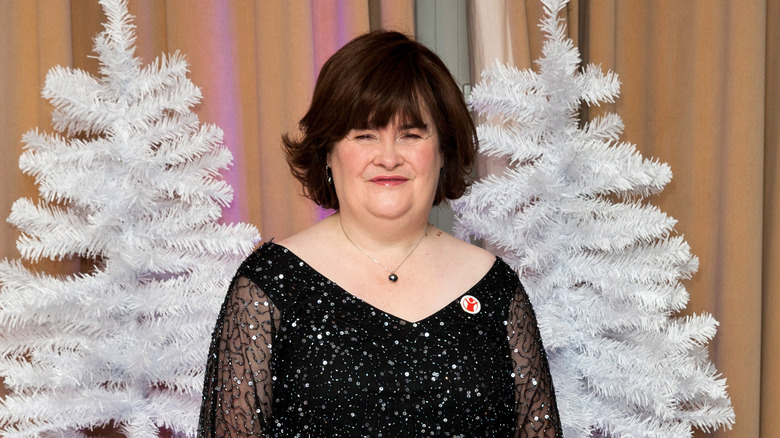 Susan Boyle in front of a two Christmas trees