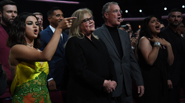 Selena Gomez alongside Andrea and Scott Swift cheering 