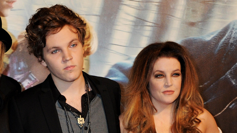 Lisa Marie and Benjamin Keough, amongst others, are standing at a booth in a carnival