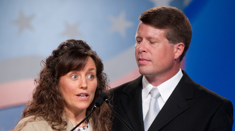 Michelle and Jim Bob Duggar standing behind a microphone