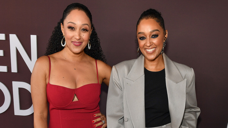 Tamera and Tia Mowry smile, standing side by side