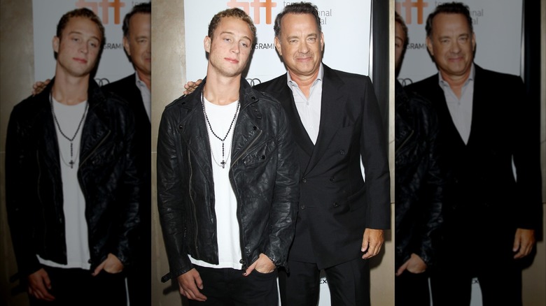 Chet Hanks in white tee and black leather jacket with father Tom Hanks in black suit