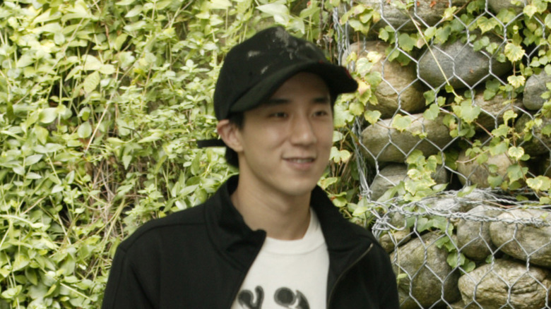 Jaycee Chan smiling in front of hedge wall