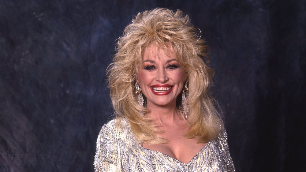 Dolly Parton smiling, wearing a silver dress