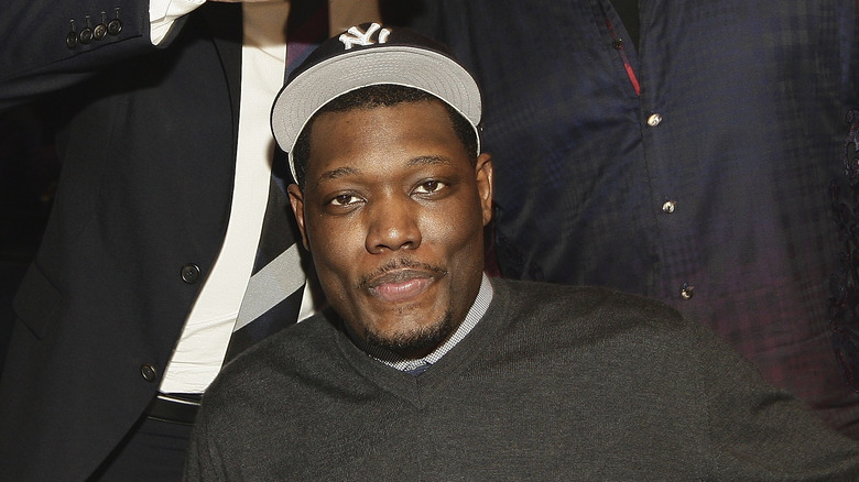 Michael Che posing in a Yankees hat 