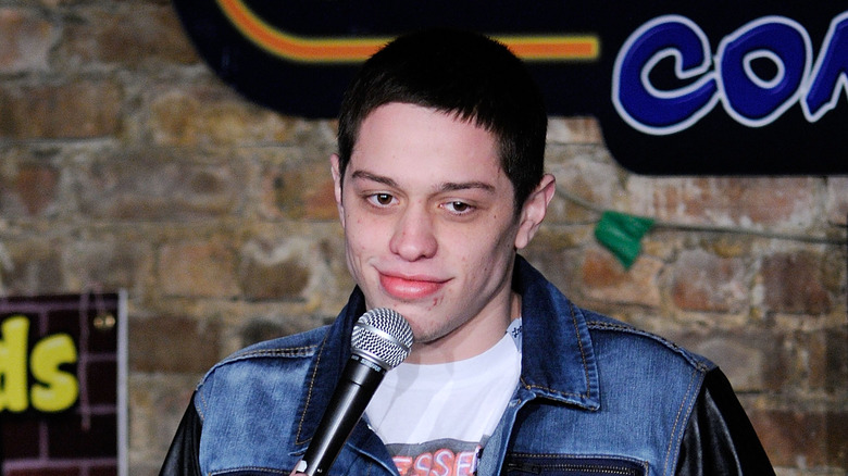 Pete Davidson performing stand-up with a mic